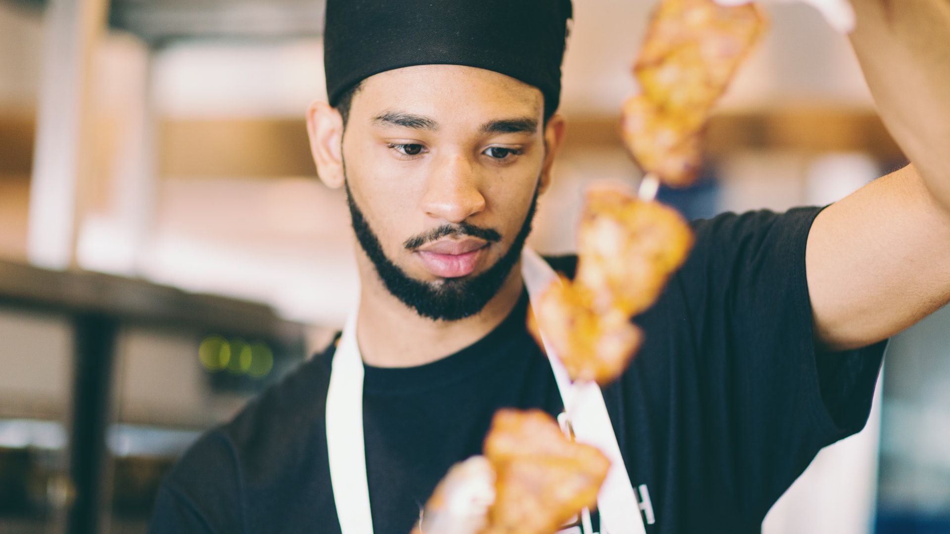 team member holding chicken skewer